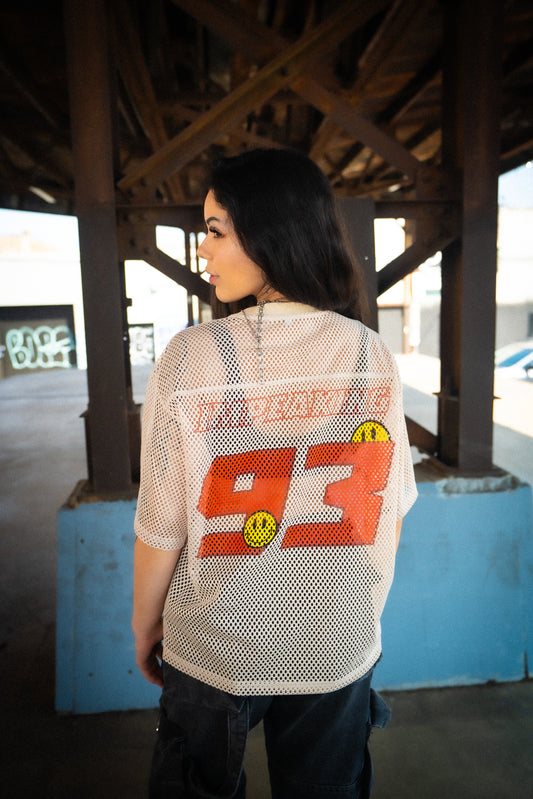 Model wearing Raver Vibes Only Legacy Jersey – Apricot beige rave jersey with oversized red 93 print, IM PEAKING lettering, and yellow smiley face details. PLUR inspired EDM festival streetwear.