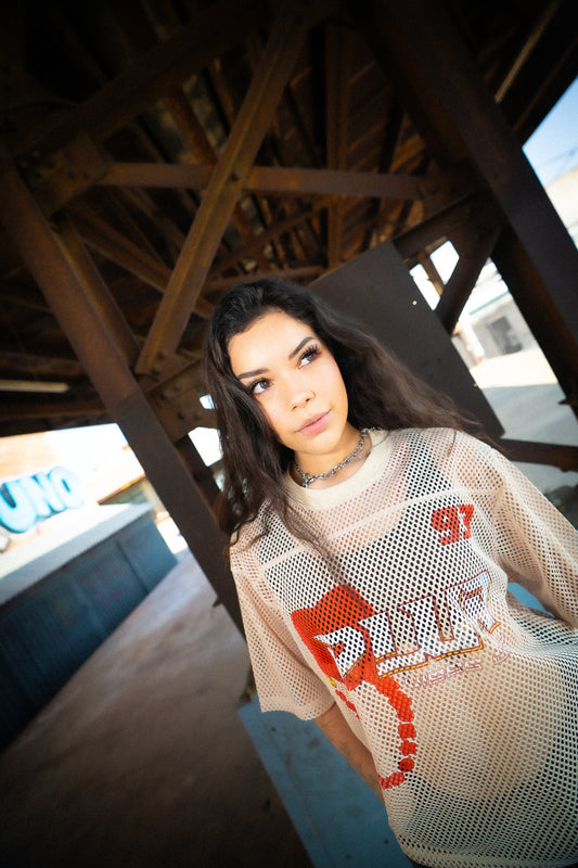 Model wearing Raver Vibes Only Legacy Jersey – Apricot beige PLUR inspired rave jersey with red 93 print, white PLUR Vibes Only logo, and kandi chain graphic. Unisex EDM festival streetwear outfit