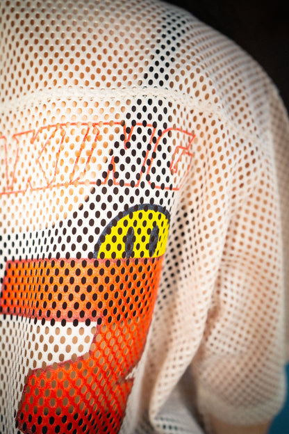 Close-up of Raver Vibes Only Legacy Jersey – IM PEAKING logo with yellow smiley face detail on beige mesh fabric. EDM festival streetwear rave jersey.