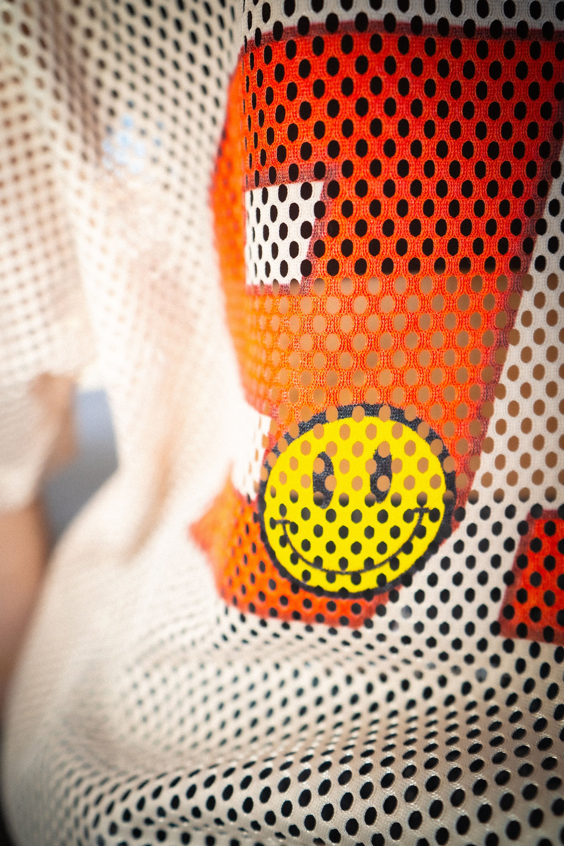 Close-up of Raver Vibes Only Legacy Jersey – yellow smiley face graphic layered on red 93 print with Apricot beige mesh texture. PLUR inspired EDM rave streetwear